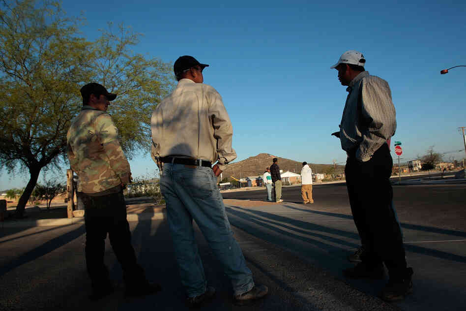 Day laborers wait on at a street corner in Tucson, Ariz., hoping for an employer to drive up and put them to work. The photograph was taken in 2008.