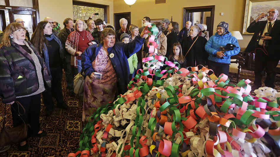 Outside the office of Utah Gov. Herbert Friday, Betsy Ogden lays paper chains on a pile symbolizing uninsured state residents who would be covered by a Medicaid expansion.