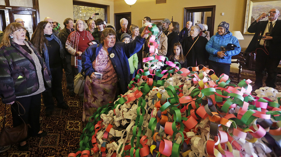 Outside the office of Utah Gov. Herbert Friday, Betsy Ogden lays paper chains on a pile symbolizing uninsured state residents who would be covered by a Medicaid expansion.