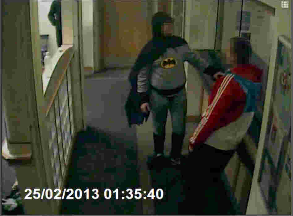 Batman brings in a wanted man to a police department in England. Batman brings in a wanted man to a police department in England.
