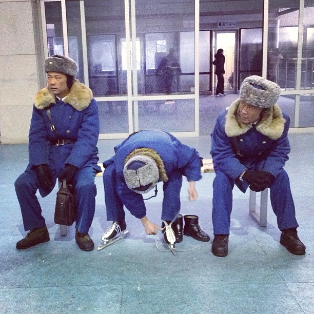 "A North Korean traffic policeman laces up his ice skates at his buddies watch at an ice skating rink in #Pyongyang."