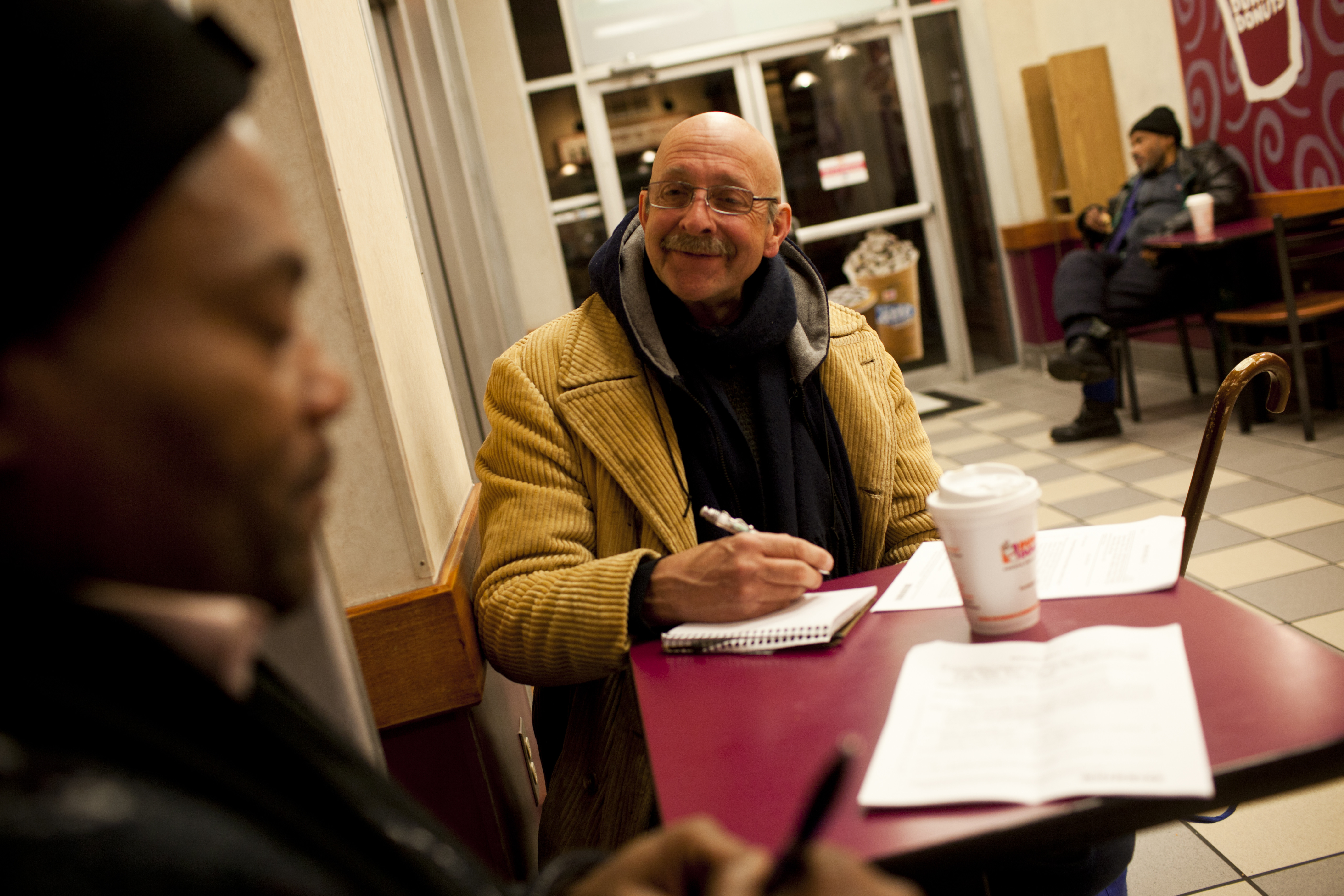 Behler lost his job as a piano tuner and has been living in shelters for a year and a half. "I'm going to find the way back," he says, "and part of this lobbying effort is making inroads in that respect." The two pass time at a 24-hour Dunkin' Donuts before HCH opens for the day.