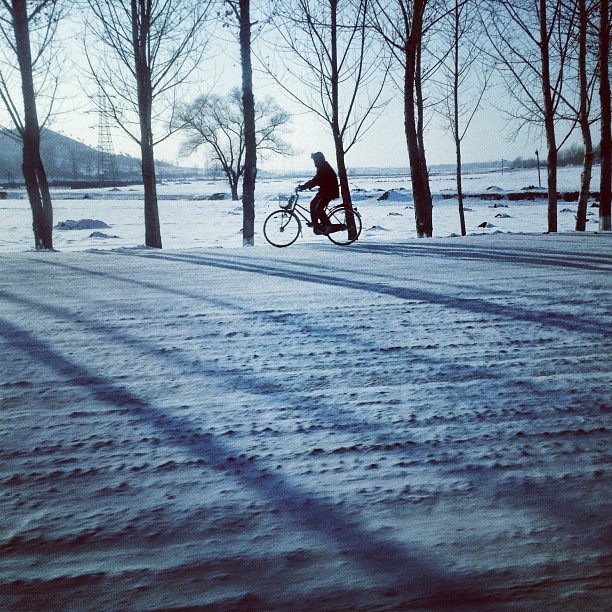 "A bicyclist rides along a snowy rural highway on the outskirts of #Pyongyang, North Korea."