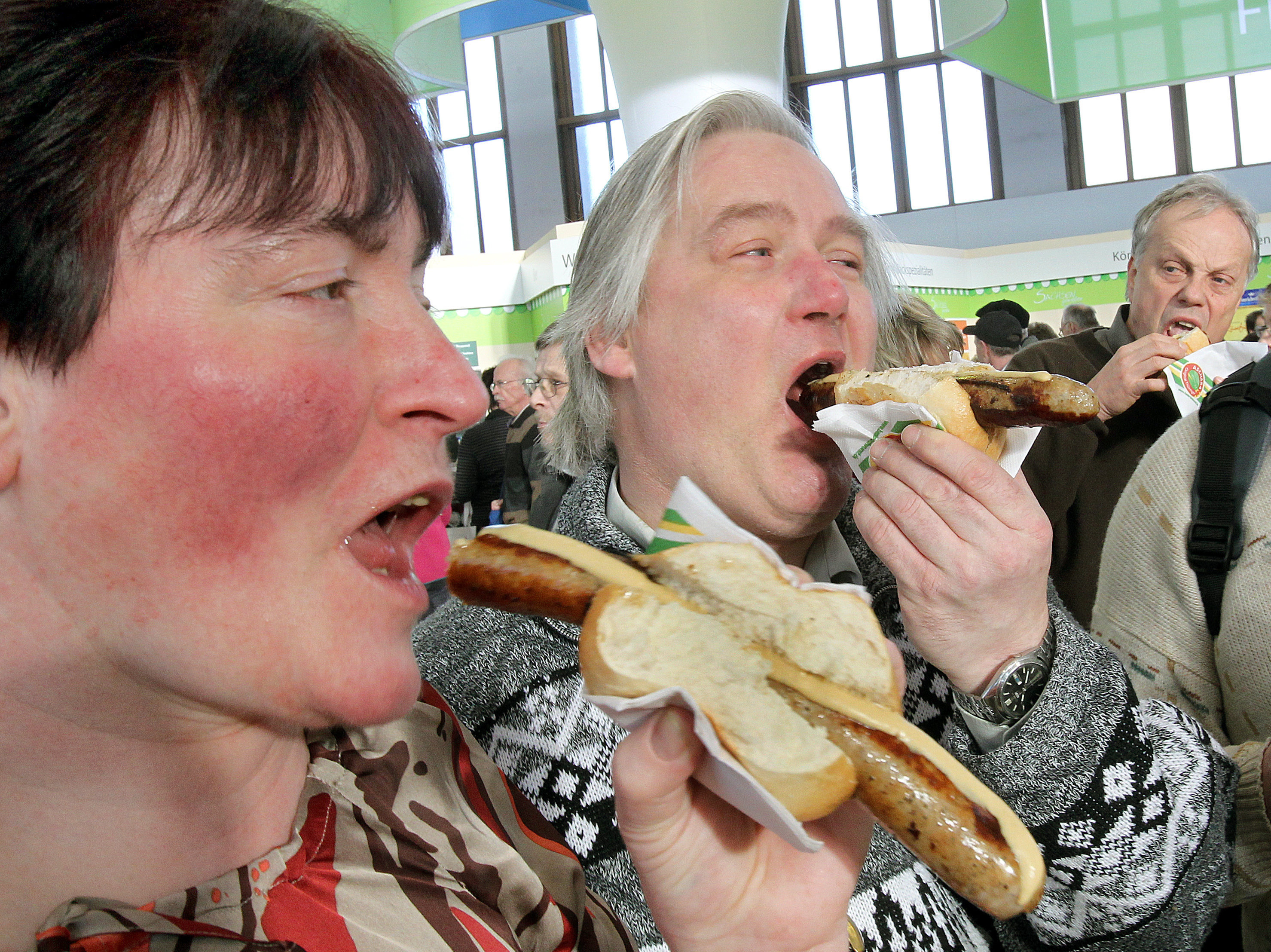 Visitors eat rostbratwurst sausages at the 