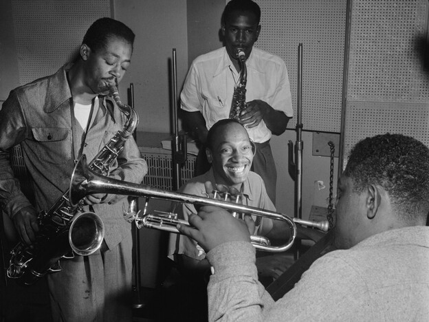 Tadd Dameron (smiling at center) was an important figure in American jazz and bebop. He is shown here with Fats Navarro on trumpet, and Charlie Rouse and Ernie Henry on saxophone.