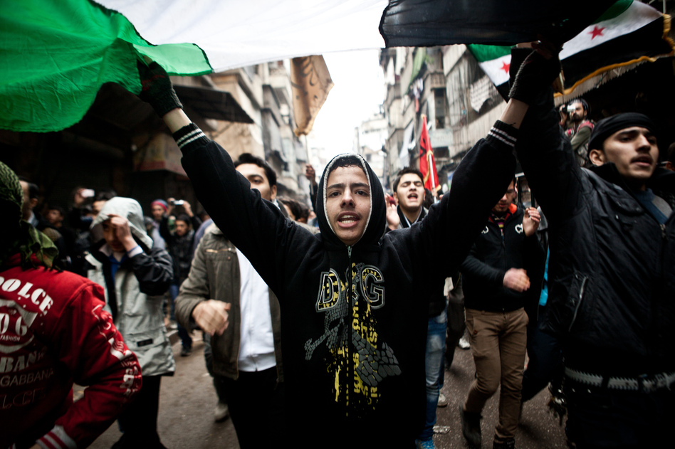 Syrians carry a large revolution flag and chant slogans during a protest in Aleppo, Syria, where young people and children sang songs against President Bashar Assad and the Syrian regime, Dec. 21, 2012.