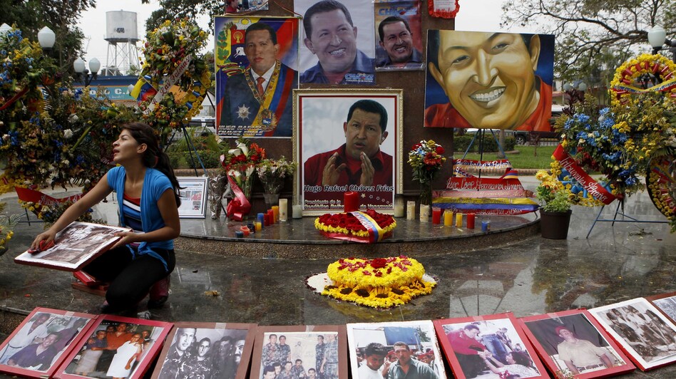 A woman wipes photos of late President Hugo Chavez at a makeshift altar for him in the main square of Sabaneta, western Venezuela, on Saturday.