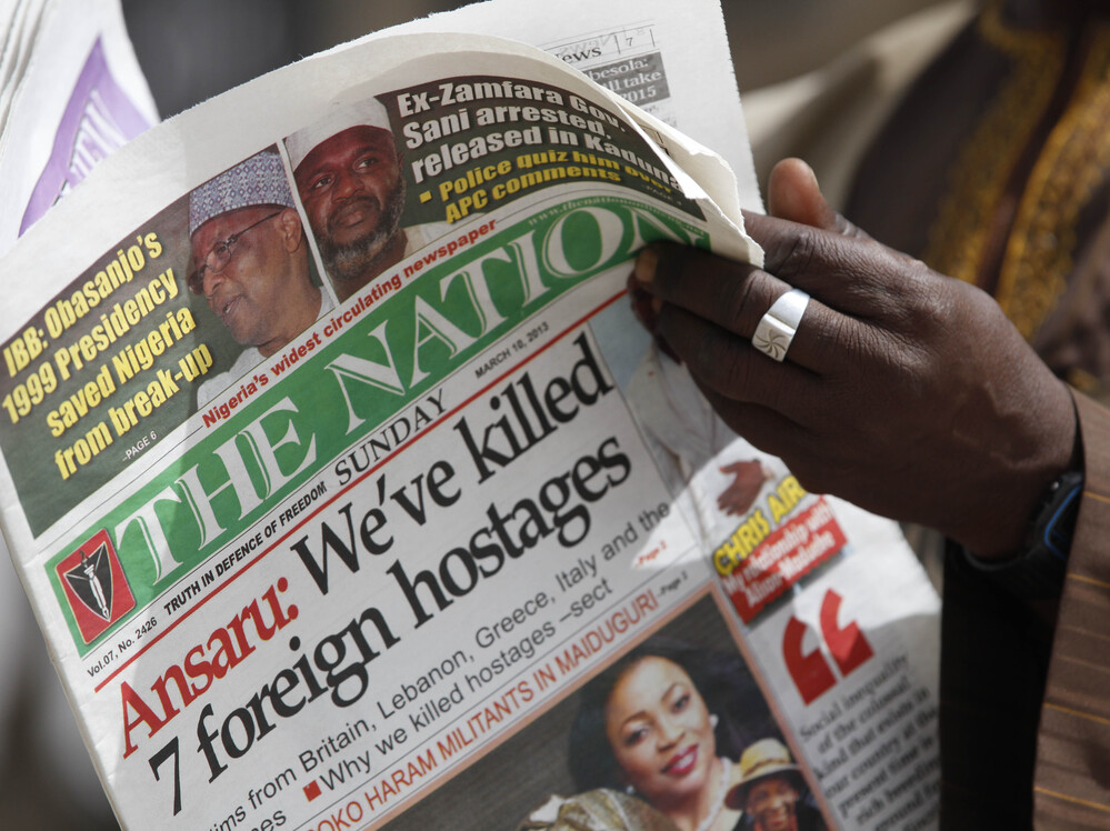 A man in Kano, Nigeria, reads a local newspaper Sunday that carries a story about the killing of seven hostages by a militant group.