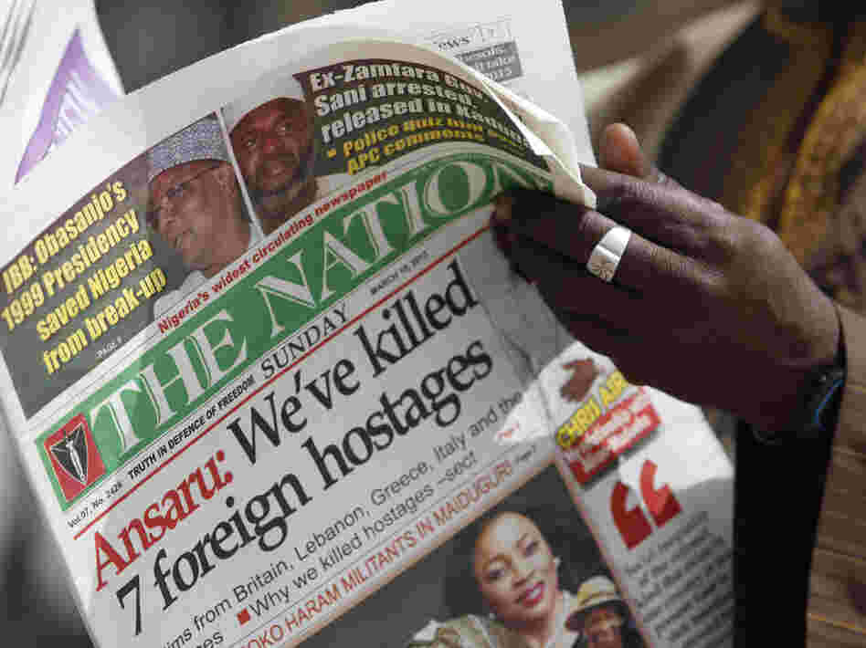 A man in Kano, Nigeria, reads a local newspaper Sunday that carries a story about the killing of seven hostages by a militant group.