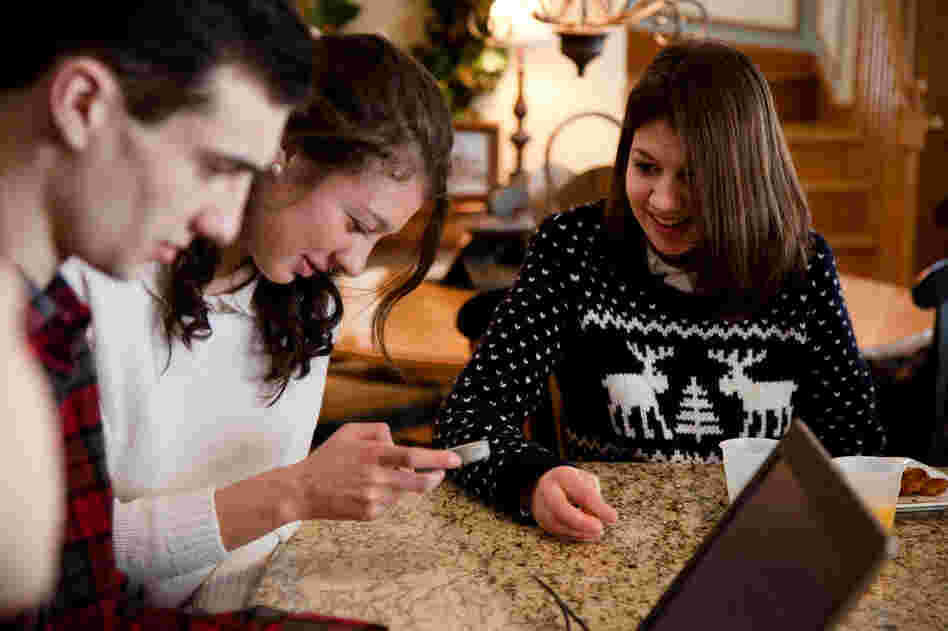 Joseph, Alexandra and Samantha Grimaldo sit around the kitchen counter in the family's home in Marlborough, Mass., playing with Samantha's voice app, though they mostly use sign language at home.