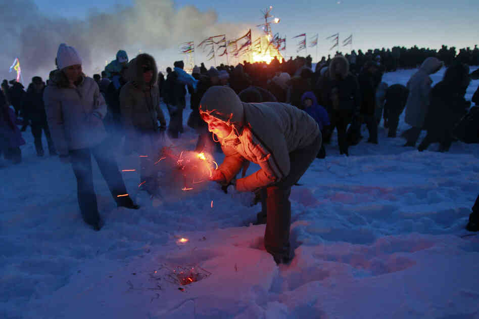 A man tries to burn a small effigy of Lady Maslenitsa during the final evening of festivities in 2011 in St. Petersburg, Russia. The torching marks the end of the holiday — a fiery goodbye to "lady winter." A larger straw effigy burns in the distance.