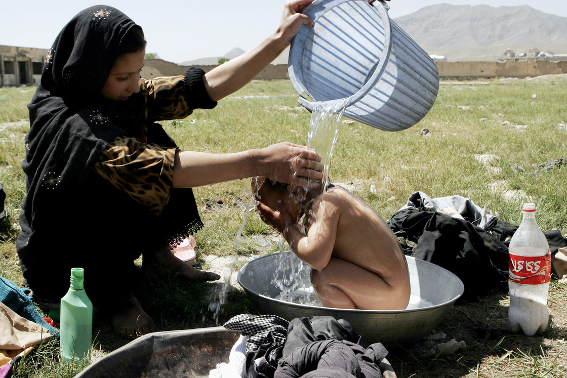 An Afghan girl bathes her brother near a building where refugees live in Kabul, 2007. An Afghan girl bathes her brother near a building where refugees live in Kabul, 2007.