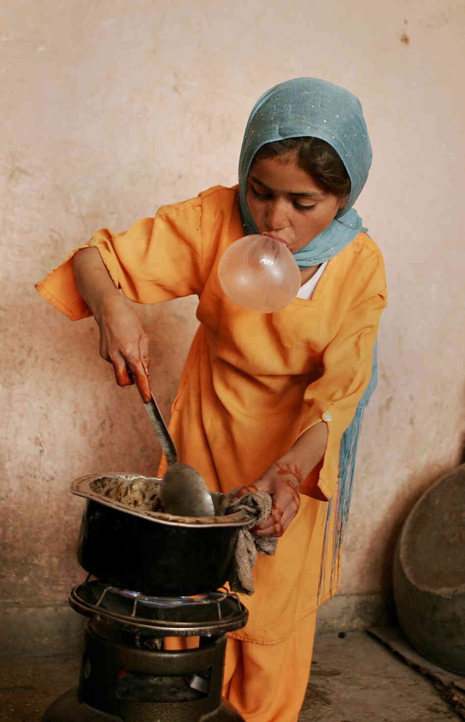An Afghan girl blows bubble gum while cooking for her family in Kabul, 2007. An Afghan girl blows bubble gum while cooking for her family in Kabul, 2007.