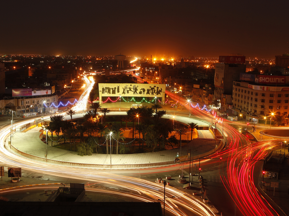 Traffic drives through Tahrir Square in central Baghdad on Wednesday. Ten years after the start of the war, bullet holes still mark buildings, and towers wrecked by U.S. missiles and tank shells have not been fully rebuilt.