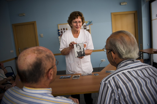 Social worker Nuria Casulleres shows a portrait of Audrey Hepburn to elderly men during a memory activity at the Cuidem La Memoria elderly home in Barcelona, Spain, last August. The home specializes in Alzheimer's patients.