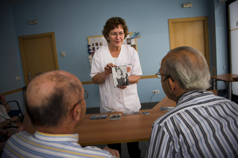 Social worker Nuria Casulleres shows a portrait of Audrey Hepburn to elderly men during a memory activity at the Cuidem La Memoria elderly home in Barcelona, Spain, last August. The home specializes in Alzheimer's patients.