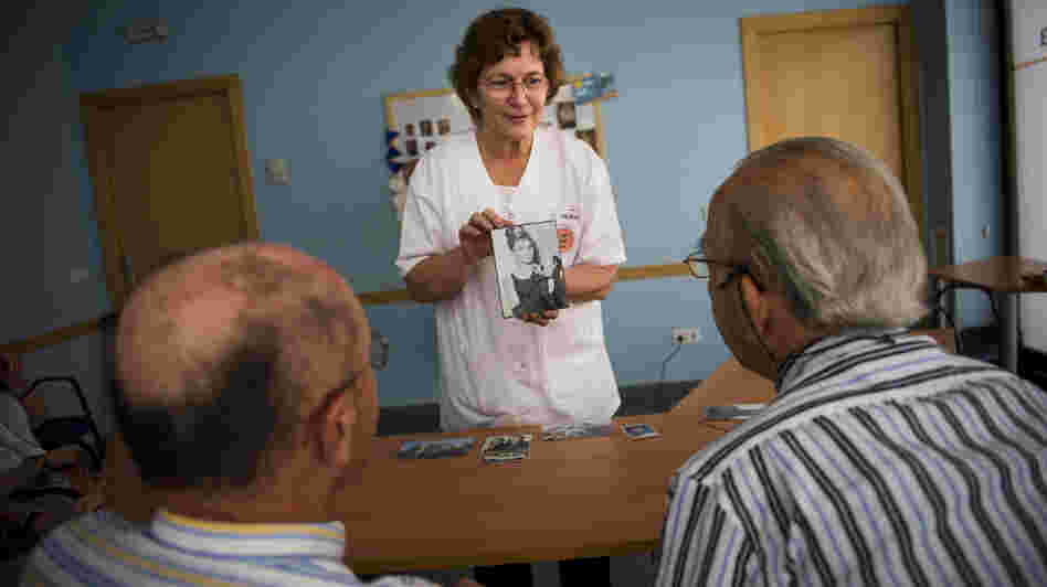 Social worker Nuria Casulleres shows a portrait of Audrey Hepburn to elderly men during a memory activity at the Cuidem La Memoria elderly home in Barcelona, Spain, last August. The home specializes in Alzheimer's patients.