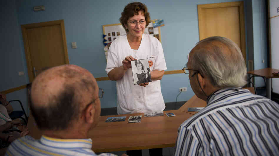 Social worker Nuria Casulleres shows a portrait of Audrey Hepburn to elderly men during a memory activity at the Cuidem La Memoria elderly home in Barcelona, Spain, last August. The home specializes in Alzheimer's patients.