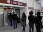 People queue to use an ATM outside of a Laiki Bank branch in Larnaca, Cyprus, on Saturday. Many rushed to cooperative banks after learning that the terms of a bailout deal with international lenders includes a one-time levy on bank deposits.