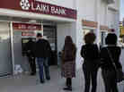 People queue to use an ATM outside of a Laiki Bank branch in Larnaca, Cyprus, on Saturday. Many rushed to cooperative banks after learning that the terms of a bailout deal with international lenders includes a one-time levy on bank deposits.