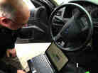 Detective Dave Wells plugs his laptop into a car's event data recorder. A large portion of new cars are equipped with the device, and the government is considering making them mandatory in all vehicles. But some say there should be an "off" option.