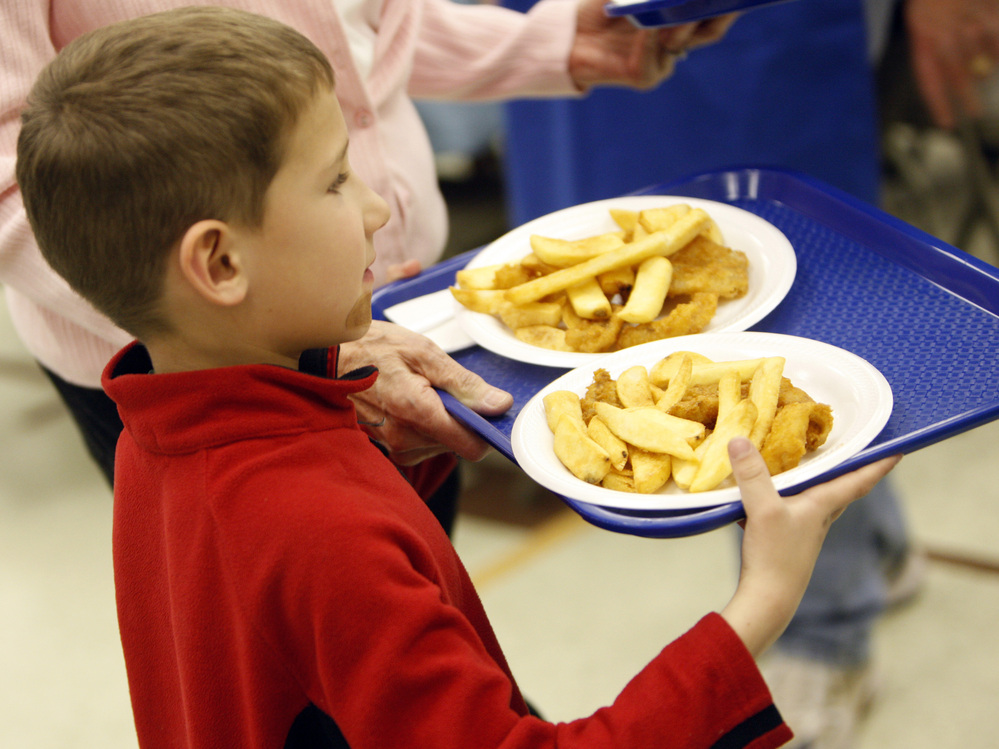 A young parishioner carries plates filled with fried fish and potatoes to a table during a Lenten Friday fish fry at St. Frances Cabrini Catholic Church in Littleton, Colo., in 2009.