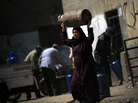 An Egyptian woman carries a cooking gas canister in Cairo on Tuesday. The government just raised the price of gas as part of an energy package needed to satisfy the conditions of a $4.8 billion IMF loan. Opponents say some of the conditions disproportionately hurt the poor. An Egyptian woman carries a cooking gas canister in Cairo on Tuesday. The government just raised the price of gas as part of an energy package needed to satisfy the conditions of a $4.8 billion IMF loan. Opponents say some of the conditions disproportionately hurt the poor.