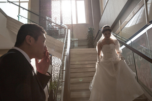Wei smokes a cigarette as his Wang comes down the stairs for their wedding.