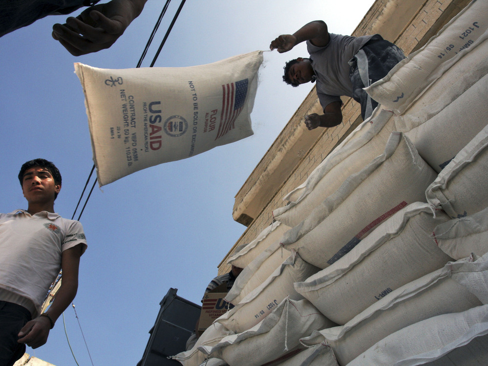 Palestinians unload bags of flour donated by USAID, or the United States Agency for International Development, at a depot in the West Bank village of Anin in 2008.