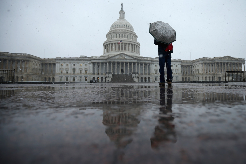 A tourist takes cover underneath an umbrella while snapping a photo of the U.S. Capitol on March 6, 2013 in Washington, DC.