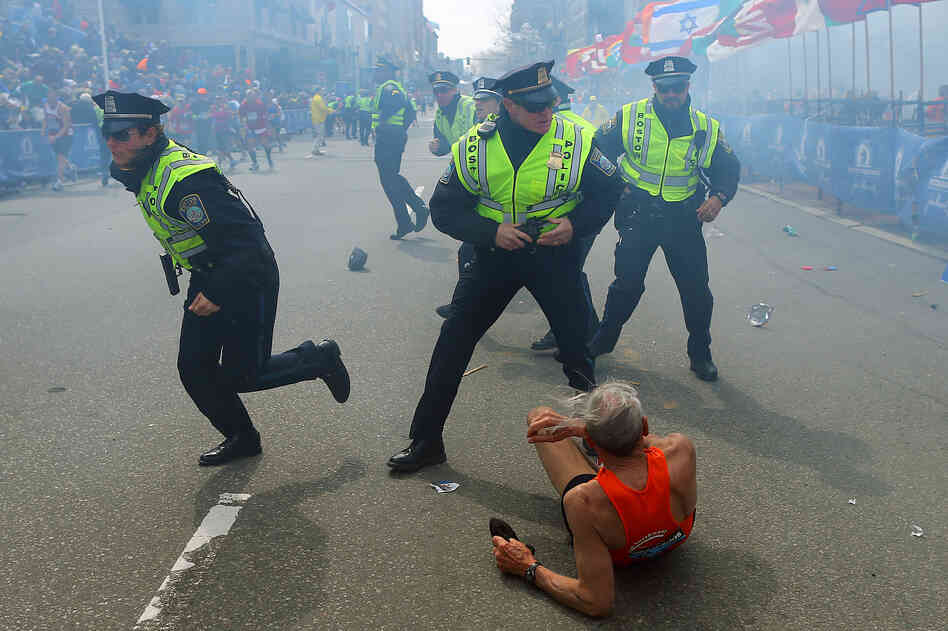 Police officers with their guns drawn hear a second explosion down the street near the finish line of the Boston Marathon. The first explosion knocked down a runner at the finish line. Police officers with their guns drawn hear a second explosion down the street near the finish line of the Boston Marathon. The first explosion knocked down a runner at the finish line.