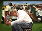Author Benjamin Alire Saenz writes about life on the U.S.-Mexico border. Here he holds his latest book, Everything Begins and Ends at the Kentucky Club, in front of "$26," a painting by Francisco Delgado (the presidents in the painting appear on American bills worth a collective $26). Author Benjamin Alire Saenz writes about life on the U.S.-Mexico border. Here he holds his latest book, Everything Begins and Ends at the Kentucky Club, in front of "$26," a painting by Francisco Delgado (the presidents in the painting appear on American bills worth a collective $26).