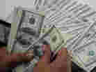 An employee at a money changer counts $100 bills in Manila on October 25, 2012.