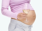 A pregnant woman holds a glass of wine. A pregnant woman holds a glass of wine.