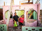 Ricardo Galvez, Giovanna Meneses Pisco and Arely Betzabe pose for a photograph in front of their former home El Ayllu. The family was back in the neighborhood to gather some of their belongings, and Giovanna spent the hours teary-eyed. As soon as families moved out, the Ministry of Transportation and Communications, with the help of paid community members, began to demolish the buildings.