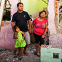 Ricardo Galvez, Giovanna Meneses Pisco and Arely Betzabe pose for a photograph in front of their former home El Ayllu. The family was back in the neighborhood to gather some of their belongings, and Giovanna spent the hours teary-eyed. As soon as families moved out, the Ministry of Transportation and Communications, with the help of paid community members, began to demolish the buildings.