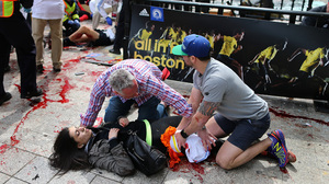 Bystanders help Sydney Corcoran at the scene of the first explosion near the finish line of the 117th Boston Marathon.