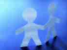 Paper cutouts of two figures holding hands on a blue background. Paper cutouts of two figures holding hands on a blue background.