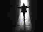 A person walks up a ramp toward a brightly lit door. A person walks up a ramp toward a brightly lit door.