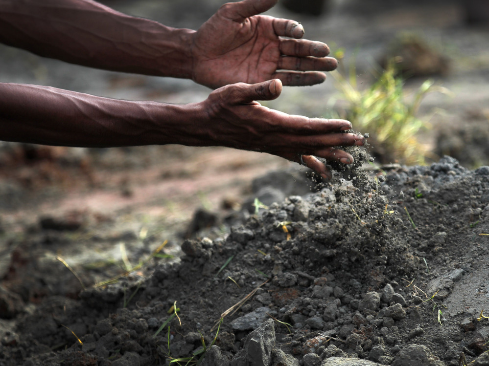 A man pours earth Wednesday onto a grave of one of the workers who died last week in the building collapse in Bangladesh.