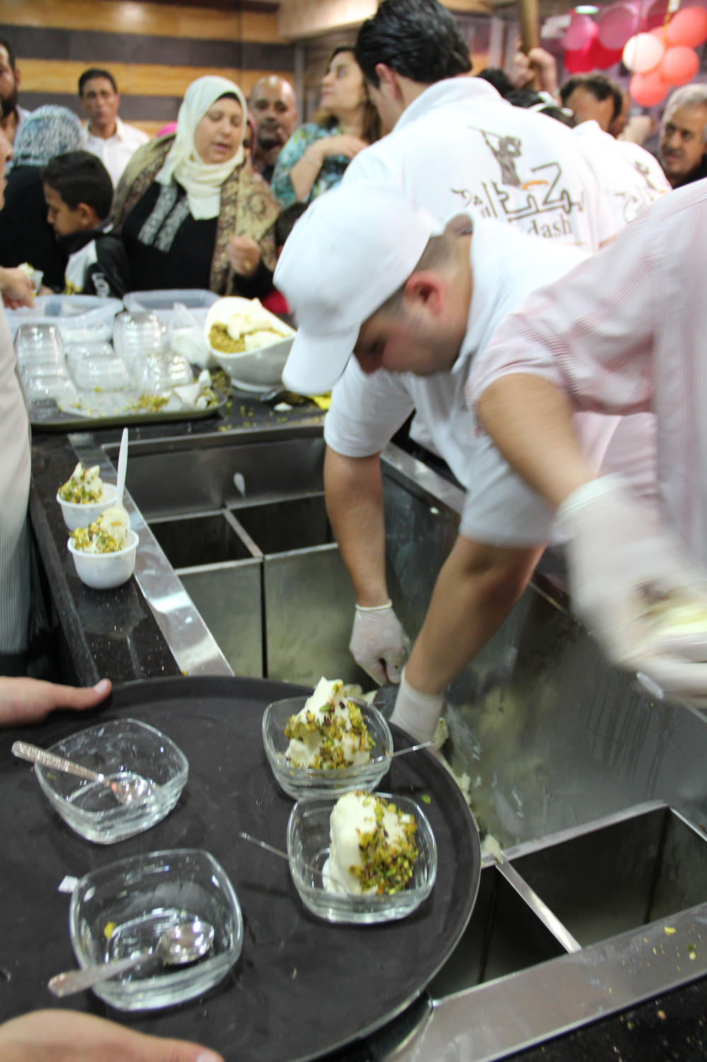 Employees scoop ice cream, which is topped with pistachios, at Bakdash's opening in Amman, Jordan, this week. Bakdash has been a landmark in Damascus, Syria, since 1895. But the war there has made it hard to get supplies, so the owners have set up a new shop in Amman.
