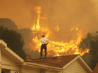 Standing on a rooftop, a man looks at the Springs fire's approaching flames in California Friday. The wildfire, reportedly, 20 percent contained, might be weakened by high humidity and cooler temperatures Saturday. Standing on a rooftop, a man looks at the Springs fire's approaching flames in California Friday. The wildfire, reportedly, 20 percent contained, might be weakened by high humidity and cooler temperatures Saturday.