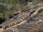 Elite U.S. Forest Service Hotshot firefighters walk the blackened edge of the Springs Fire near Camarillo, California. Citing favorable weather, officials say the fire could be contained Monday. Elite U.S. Forest Service Hotshot firefighters walk the blackened edge of the Springs Fire near Camarillo, California. Citing favorable weather, officials say the fire could be contained Monday.