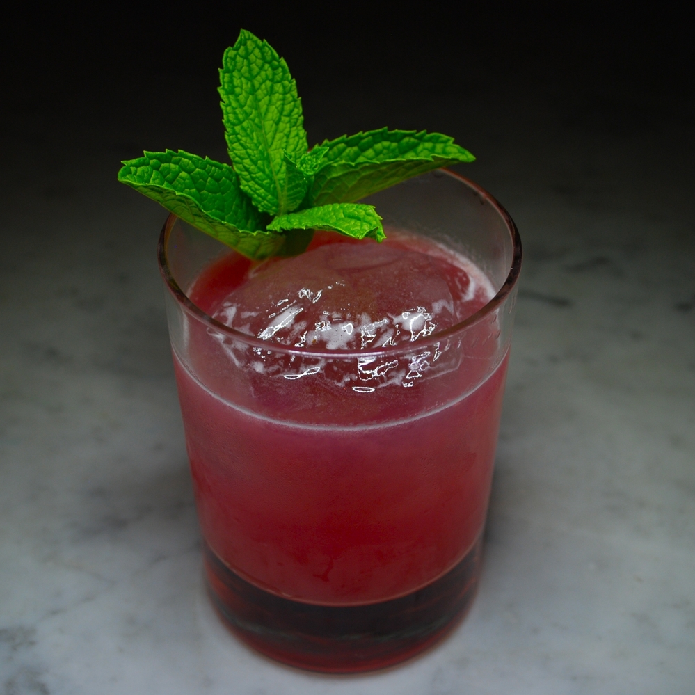 World Shattered, a cocktail by Tyler Fry of the Chicago bar The Violet Hour. The drink includes R. Franklin's Original Recipe Malort, and tames the bitterness with lemon, honey syrup, raspberry and mint.