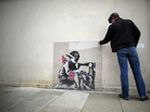 A man inspects a plastic cover placed over Slave Labour, an artwork attributed to Banksy, in London. This piece of art was put up for sale in Miami last February, but the ensuing outrage led to the auction's cancellation. The mural is now part of an exhibition in London, and is is expected to move to the U.S. afterward. A man inspects a plastic cover placed over Slave Labour, an artwork attributed to Banksy, in London. This piece of art was put up for sale in Miami last February, but the ensuing outrage led to the auction's cancellation. The mural is now part of an exhibition in London, and is is expected to move to the U.S. afterward.