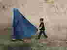 A boy holds the burqa of his mother as they walk down a street in the old city of Kabul on November 1, 2009.