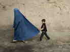 A boy holds the burqa of his mother as they walk down a street in the old city of Kabul on November 1, 2009.