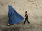 A boy holds the burqa of his mother as they walk down a street in the old city of Kabul on November 1, 2009. A boy holds the burqa of his mother as they walk down a street in the old city of Kabul on November 1, 2009.