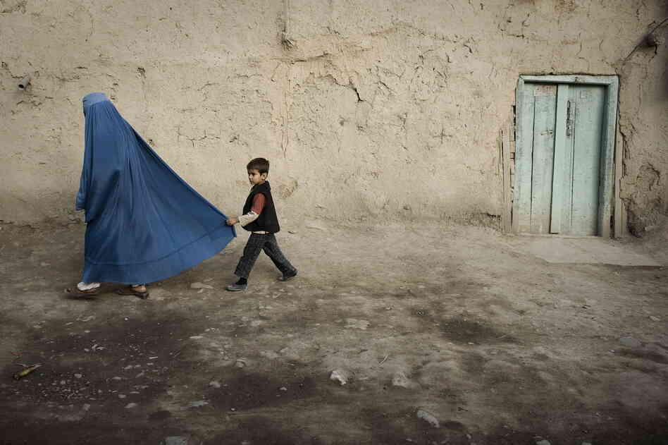 A boy holds the burqa of his mother as they walk down a street in the old city of Kabul on November 1, 2009. A boy holds the burqa of his mother as they walk down a street in the old city of Kabul on November 1, 2009.