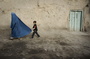 A boy holds the burqa of his mother as they walk down a street in the old city of Kabul on November 1, 2009.